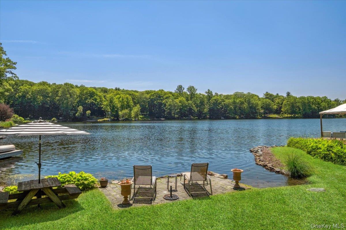 Dock with a water view, a lawn, and a view of trees