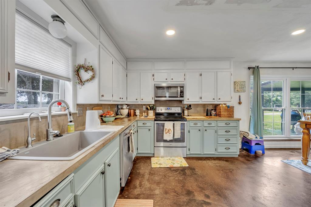 9822 Nasturtium Road Ore City, TX 75683 - Photo 24 of 37 a kitchen with stainless steel appliances kitchen island granite countertop a sink and cabinets