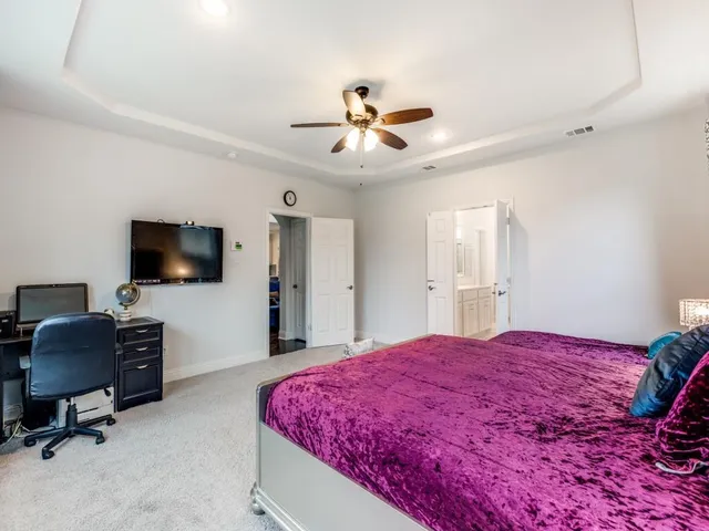 a spacious bedroom with a bed and a flat screen tv