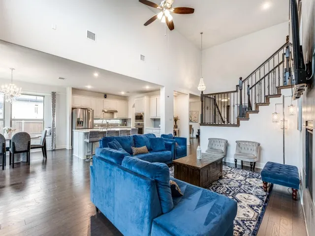 a living room with couches kitchen view and a dining table with wooden floor