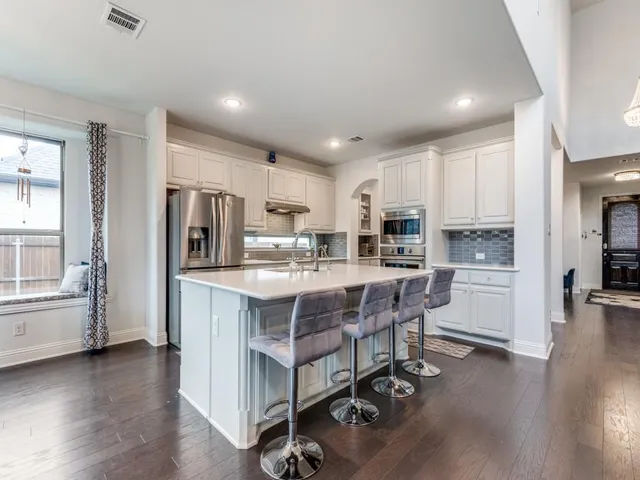 a kitchen with stainless steel appliances granite countertop a refrigerator a sink dishwasher a stove and a refrigerator with wooden floor