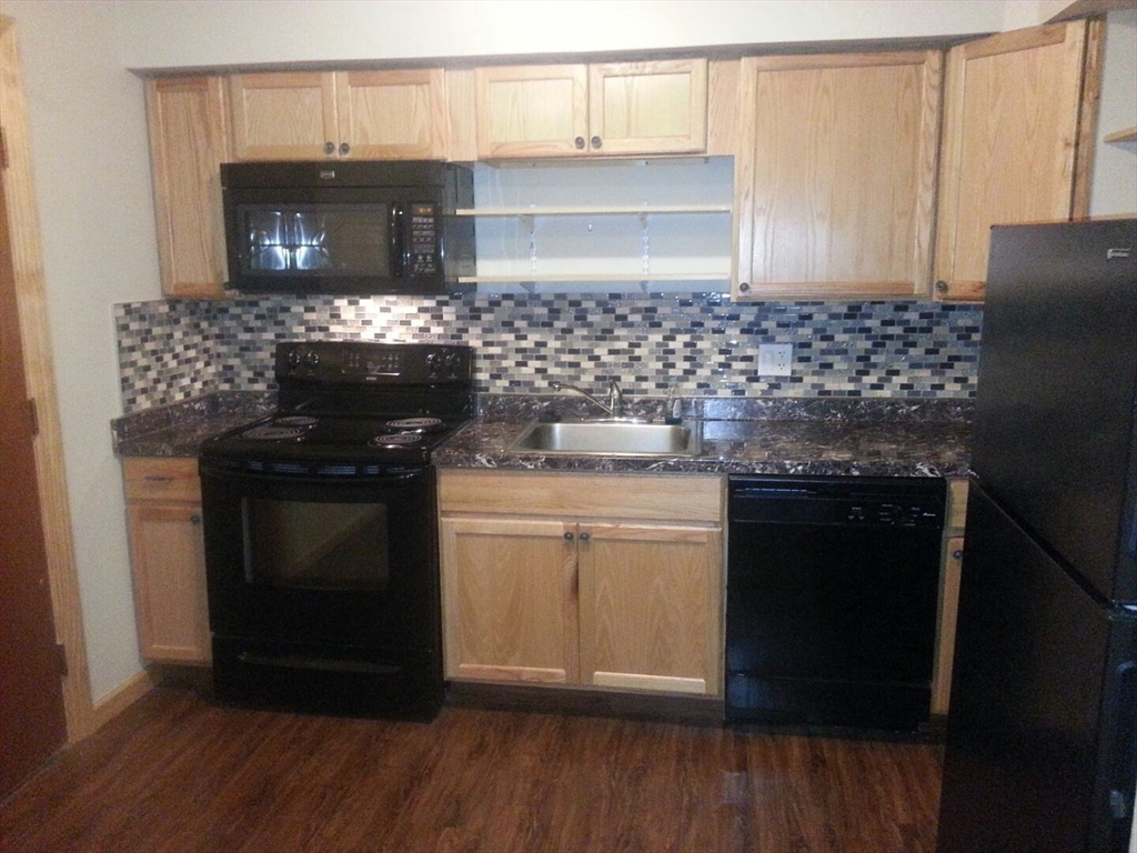 a kitchen with granite countertop a stove and a wooden floor