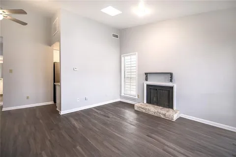 a view of an empty room with wooden floor fireplace and a window