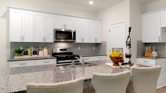 1220 Pavo Path Wendell, NC 27591 - Photo 4 of 26 a kitchen with a sink a stove and cabinets