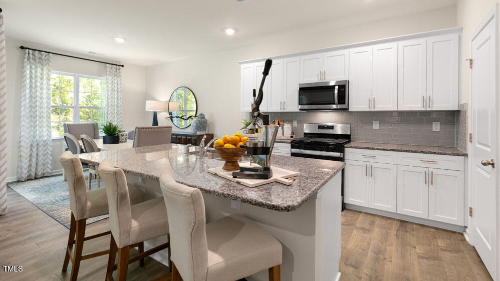 1220 Pavo Path Wendell, NC 27591 - Photo 5 of 26 a kitchen with stainless steel appliances granite countertop a stove a sink a microwave a dining table and chairs