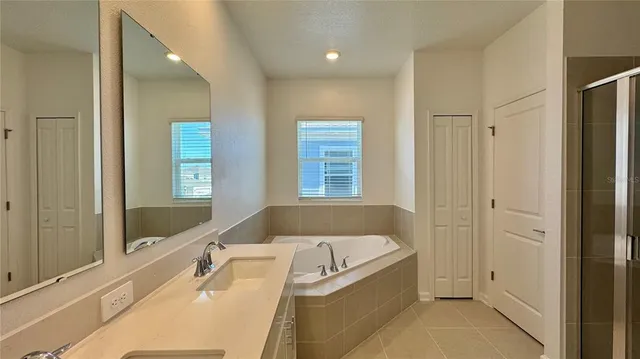 a spacious bathroom with a tub sink and mirror