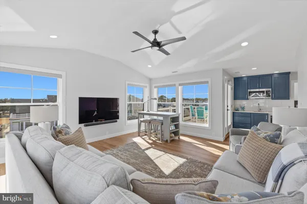 a living room with furniture and a flat screen tv with kitchen view