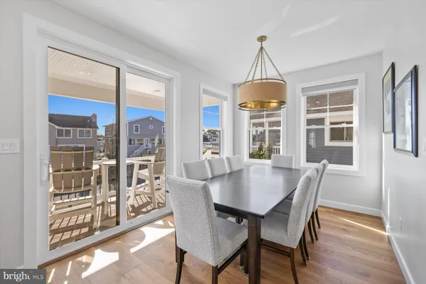 a dining room with wooden floor a chandelier a glass table and chairs