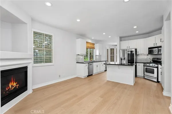 a large kitchen with stainless steel appliances kitchen island a large counter top and a fireplace