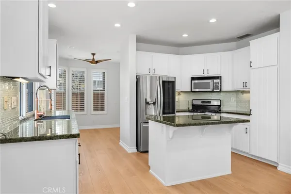 a kitchen with stainless steel appliances granite countertop a refrigerator a stove a sink a stove and a microwave