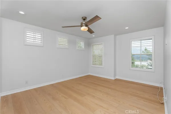 a view of empty room with wooden floor and fan
