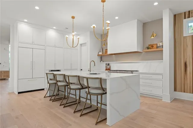 a large white kitchen with a large island in the center