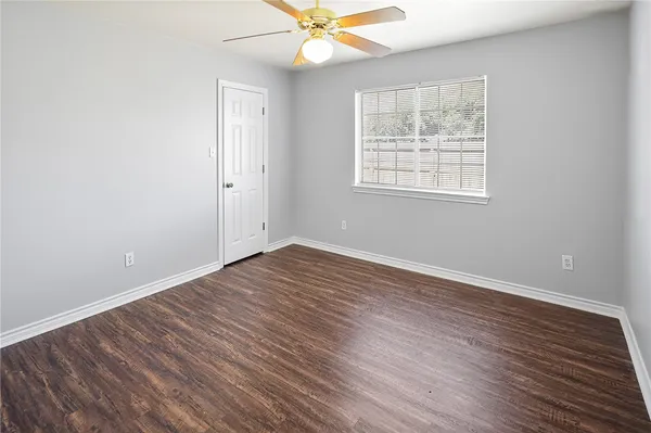 an empty room with wooden floor fan and windows