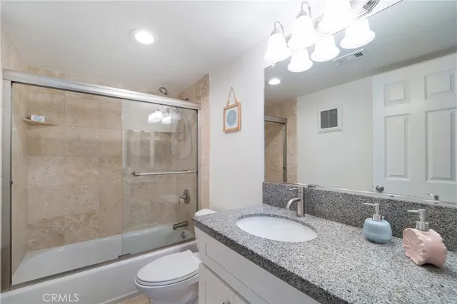 a bathroom with a granite countertop sink a toilet and a large mirror