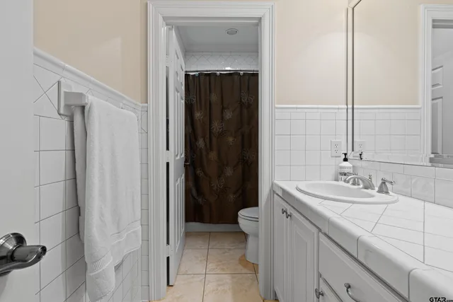 a spacious bathroom with a granite countertop sink a toilet and a mirror
