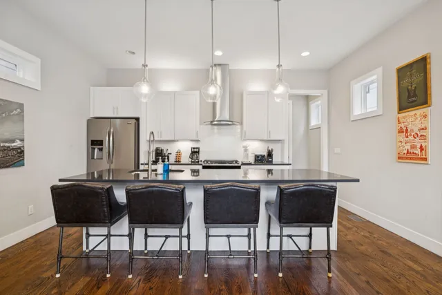 a kitchen with stainless steel appliances granite countertop a stove a sink a refrigerator a dining table and chairs with wooden floor