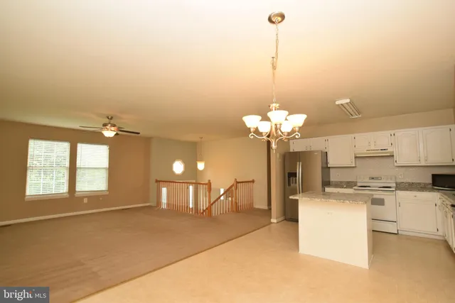 a view of a kitchen with a sink a refrigerator and a chandelier