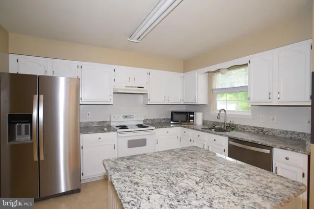 a kitchen with granite countertop a refrigerator sink stove and oven