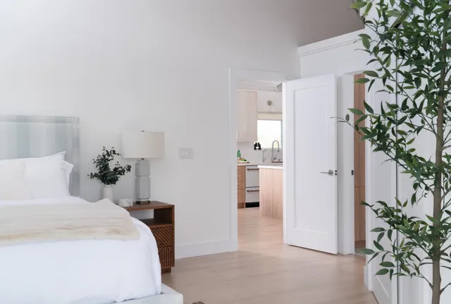 a bedroom with a large bed and a potted plant