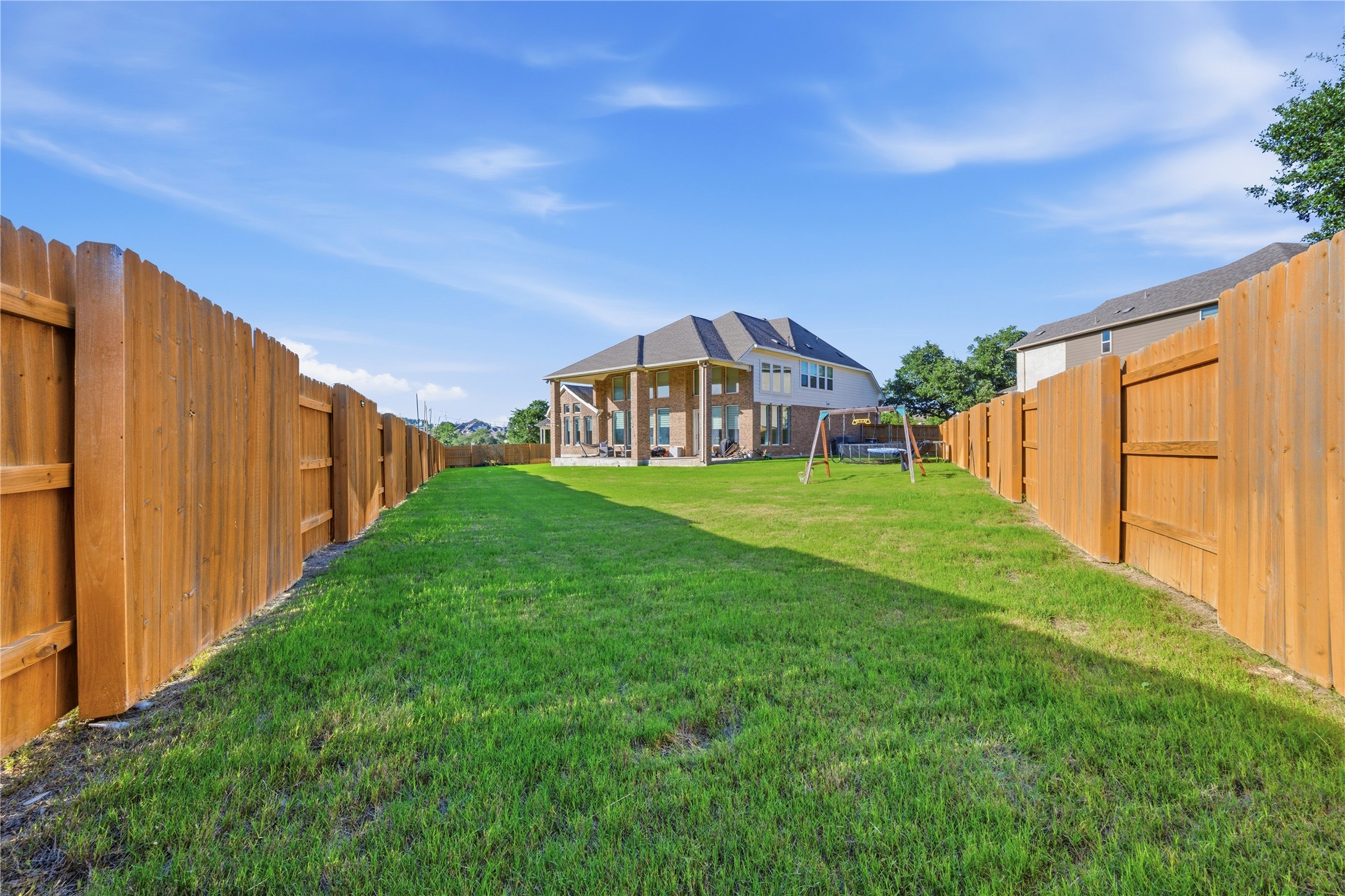 105 Autumn Oak Way Georgetown, TX 78628 - Photo 40 of 40 Expansive backyard featuring a manicured lawn, full wood fencing, and a two-story brick exterior