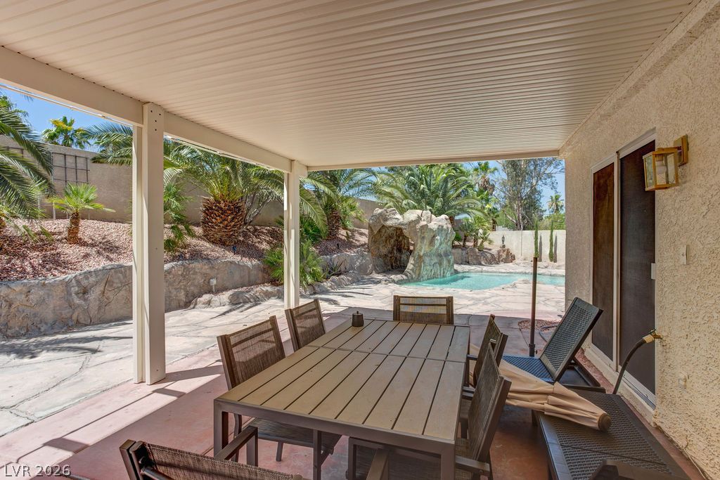 1 Rising Sun Court Henderson, NV 89074 - Photo 36 of 47 Covered patio with ample seating overlooks a sparkling pool and lush landscaping.