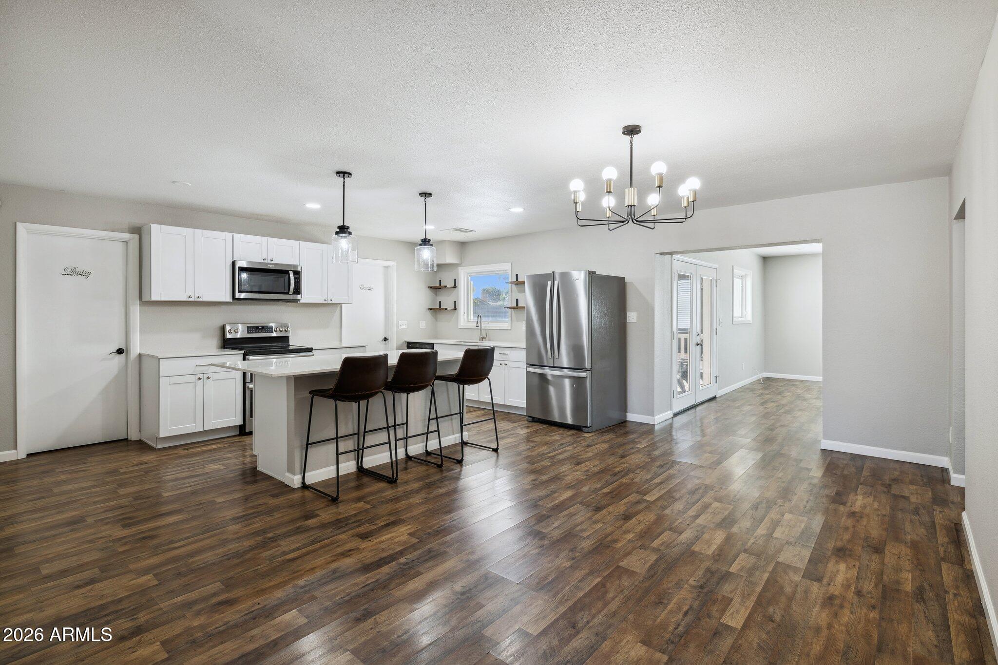 13002 North 28th Place Phoenix, AZ 85032 - Photo 9 of 42 a open kitchen with stainless steel appliances granite countertop a stove top oven a refrigerator a dining table and chairs with wooden floor