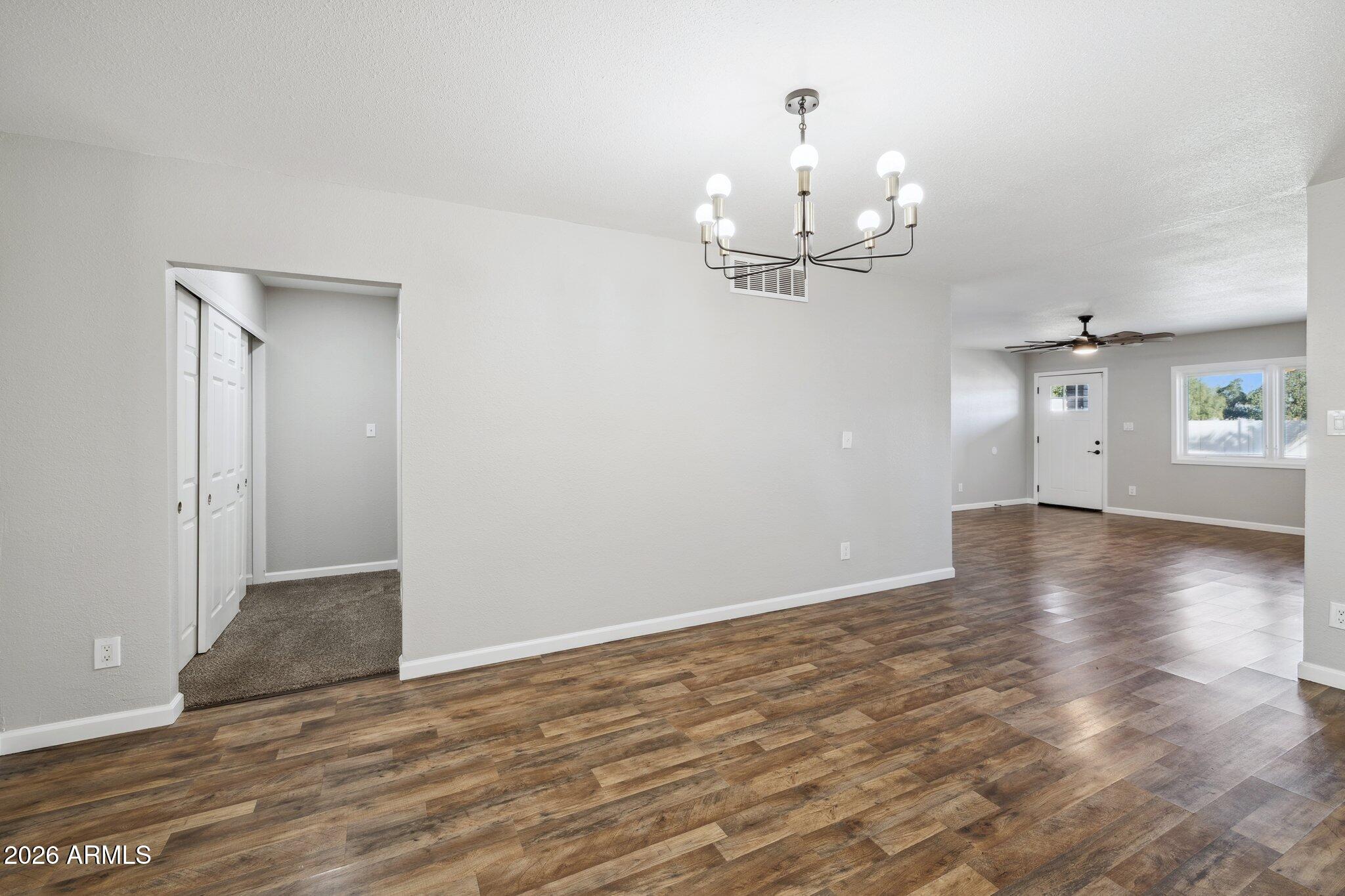 13002 North 28th Place Phoenix, AZ 85032 - Photo 14 of 42 an empty room with wooden floor and chandelier