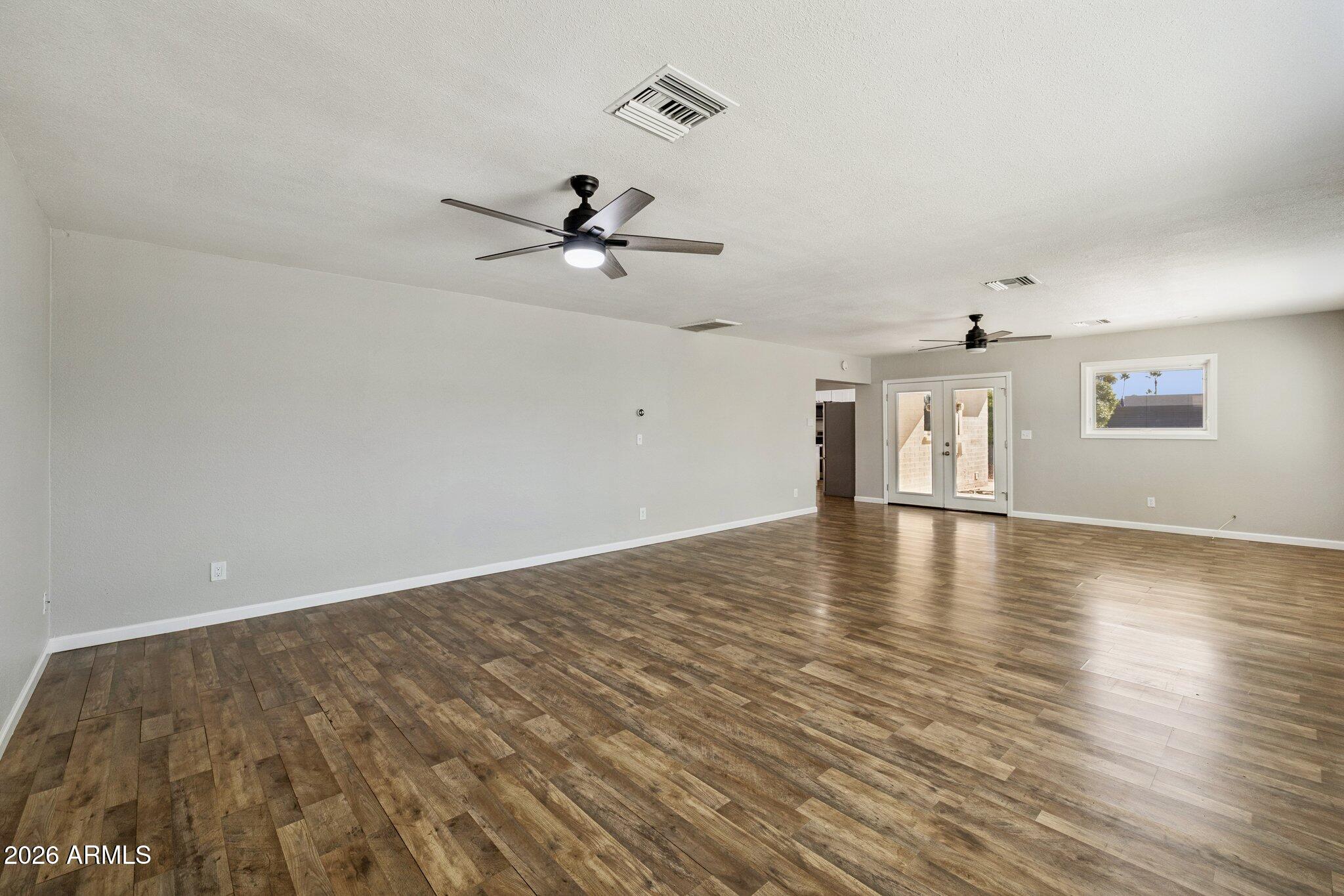 13002 North 28th Place Phoenix, AZ 85032 - Photo 17 of 42 a view of empty room with wooden floor and ceiling fan