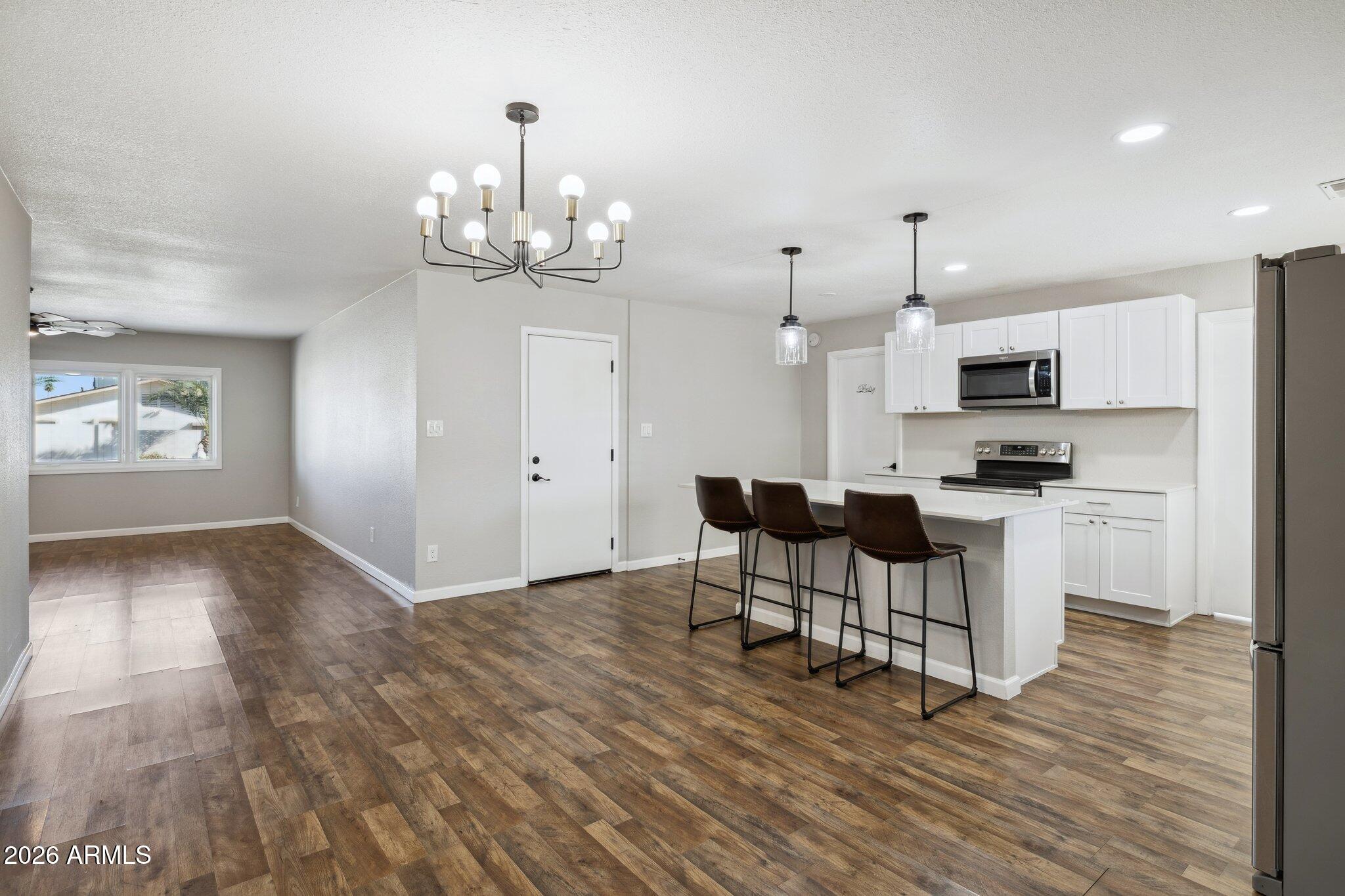 13002 North 28th Place Phoenix, AZ 85032 - Photo 8 of 42 a kitchen with stainless steel appliances granite countertop a stove top oven a refrigerator a sink and a dining table with wooden floor