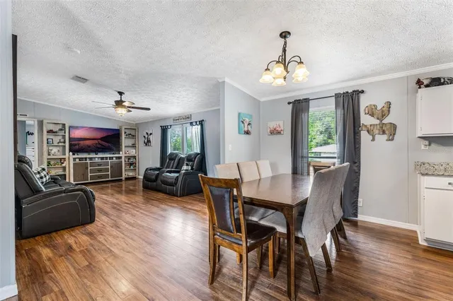 a view of a dining room and livingroom with furniture wooden floor a chandelier