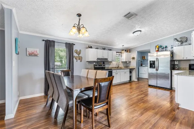 a kitchen with granite countertop a refrigerator oven a sink dishwasher and white cabinets with wooden floor