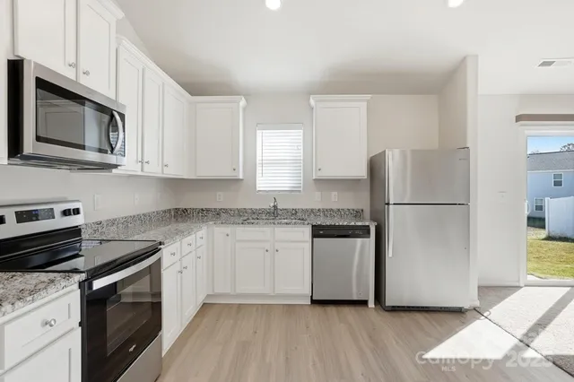 a kitchen with stainless steel appliances granite countertop a refrigerator stove a sink and dishwasher with wooden floor