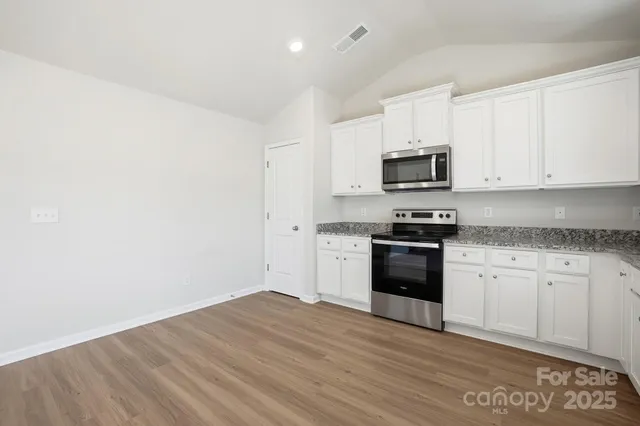 a kitchen with granite countertop white cabinets and stainless steel appliances
