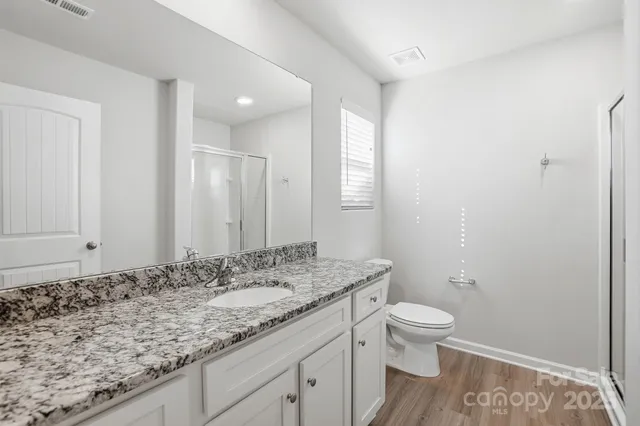 a bathroom with a granite countertop sink a toilet and a mirror