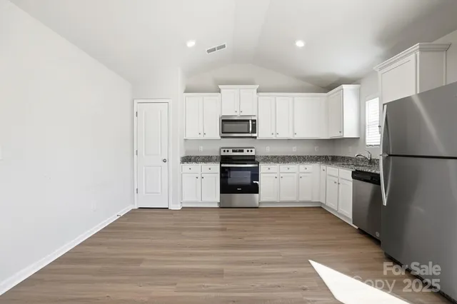 a kitchen with granite countertop a refrigerator stove top oven and cabinets