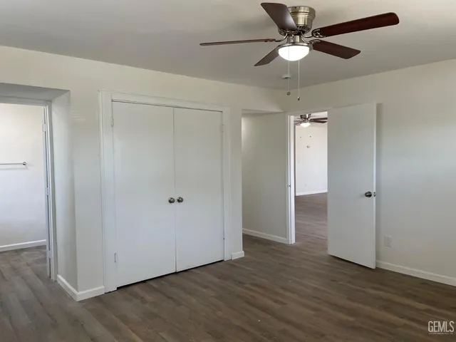 an empty room with wooden floor fan and windows