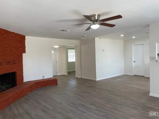 a view of an empty room with wooden floor and a fireplace