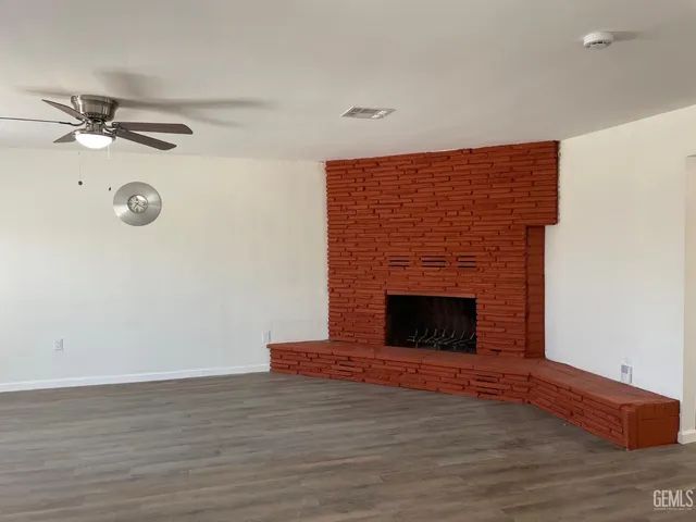 a view of empty room with wooden floor and fireplace