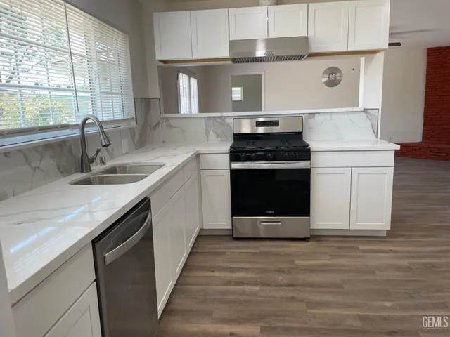 a kitchen with stainless steel appliances granite countertop a stove a sink and a microwave