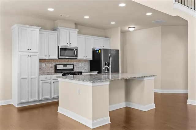 a kitchen with granite countertop a stove a sink and a microwave