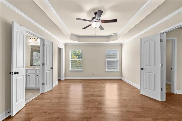 a view of an empty room with wooden floor and a ceiling fan