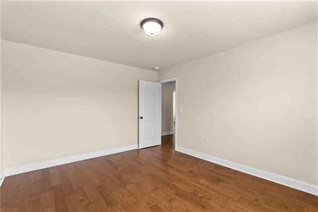 a view of an empty room with wooden floor and a ceiling fan