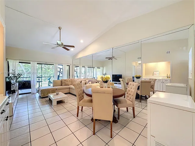 a kitchen with stainless steel appliances kitchen island granite countertop a table chairs in it and wooden floors