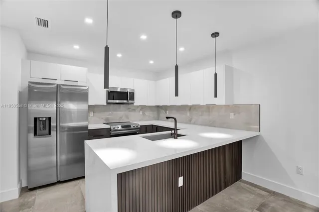 a kitchen with stainless steel appliances granite countertop a sink a refrigerator and a stove