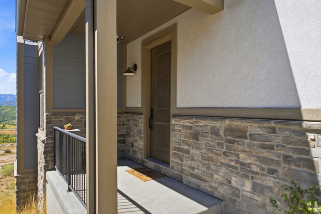 6039 North Westridge Road Heber City, UT 84032 - Photo 53 of 71 Entryway featuring stone facade, stucco exterior, covered porch, and mountain backdrop