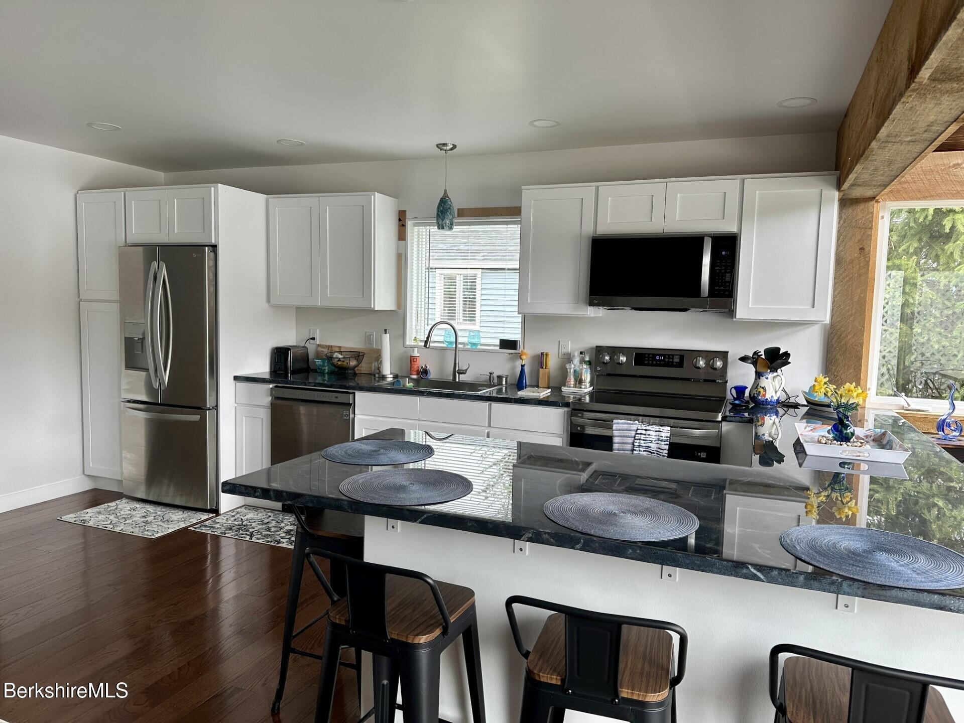 210 Shore Road Richmond, MA 01201 - Photo 3 of 22 a kitchen with a table chairs microwave and refrigerator