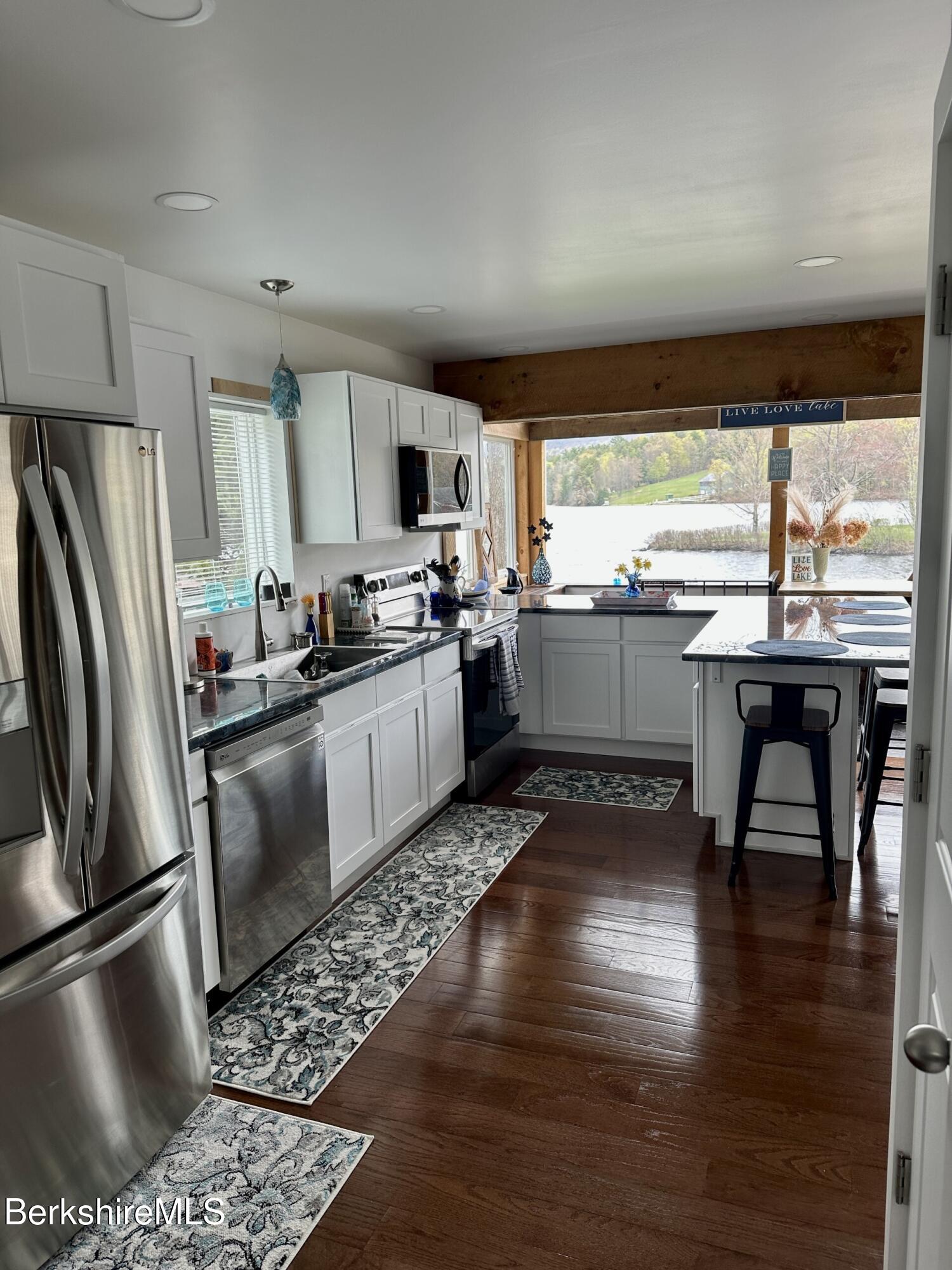 210 Shore Road Richmond, MA 01201 - Photo 5 of 22 a kitchen with stainless steel appliances granite countertop a refrigerator a stove a sink a dining table and chairs