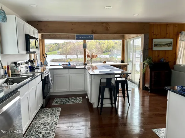 a kitchen with stainless steel appliances granite countertop a stove top oven a sink with wooden cabinets and dining table