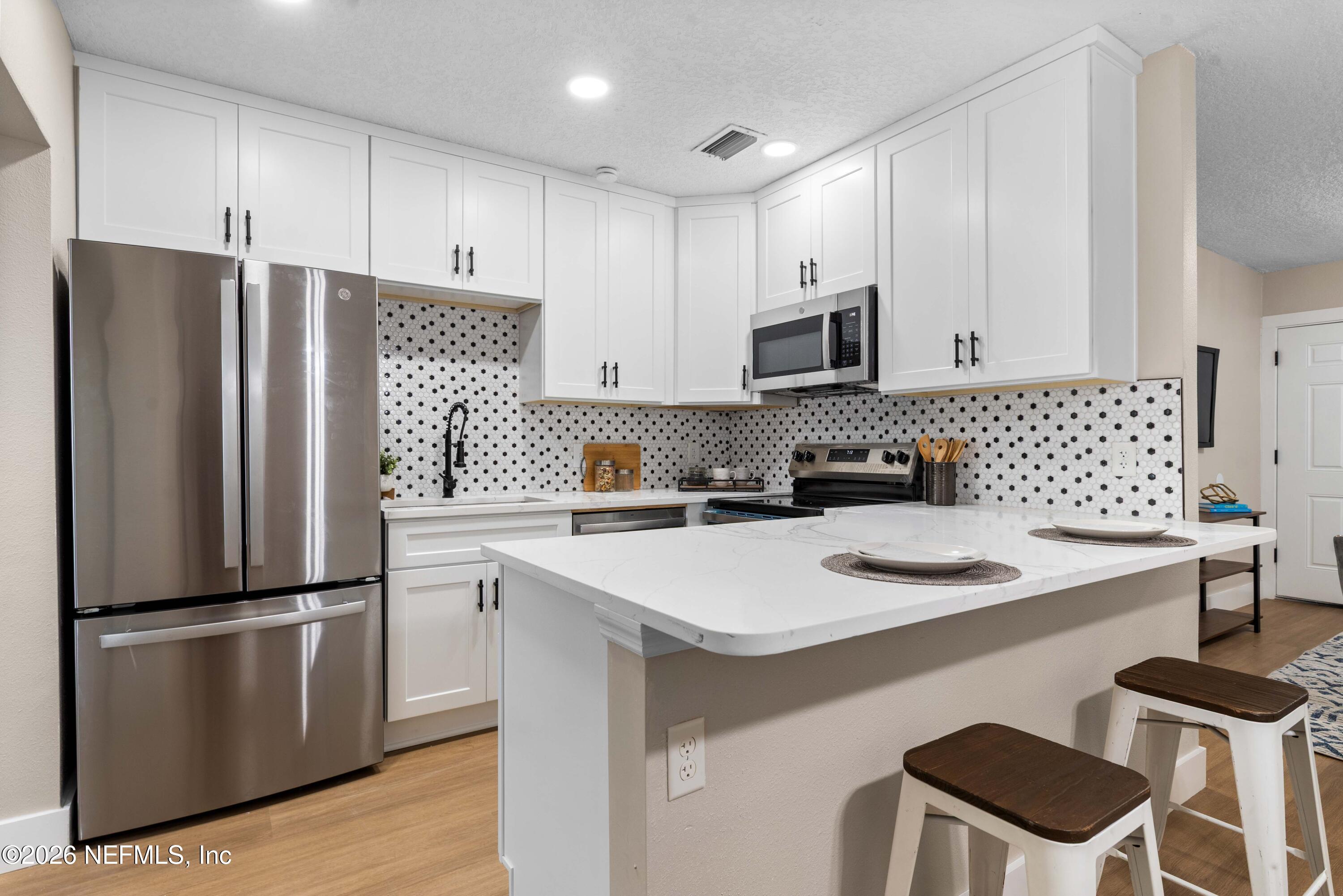 529 Sapelo Road Jacksonville, FL 32216 - Photo 12 of 31 a kitchen with a refrigerator a stove a sink and white cabinets