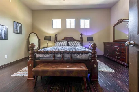 a bedroom with a bed and a dresser with wooden floor